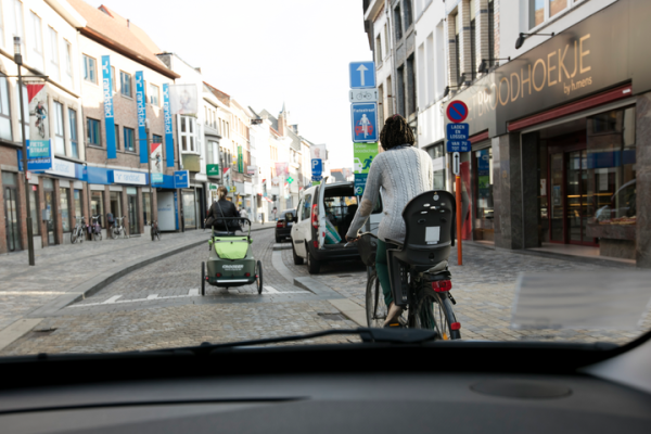 fietser en fietser met fietskar in een fietszone, eenrichtingsstraag, automobilist rijdt achter de fietsers