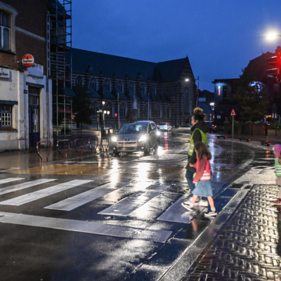 voetgangers oversteken op een zebrapad met fluohesje