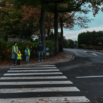 oversteken aan een zebrapad in het schemerdonker, moeder met kinderen in fluohesje