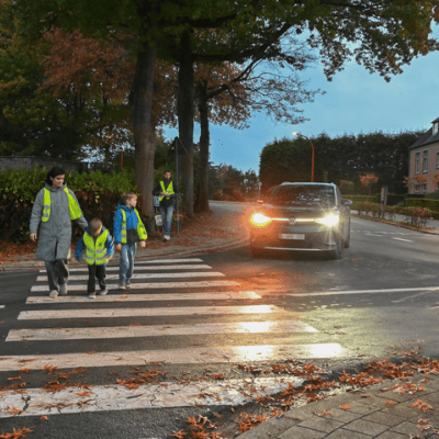 voetganger met een fluohesje die oversteken aan en zebrapad, auto slaat links af