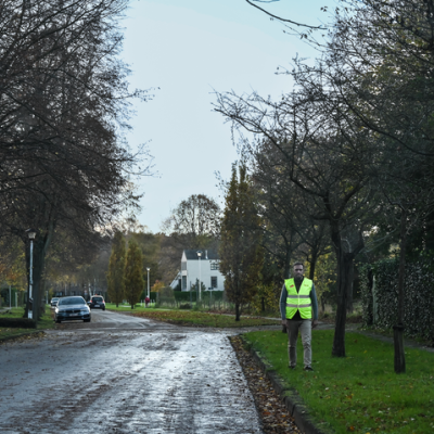 voetganger die op vehoogde berm stapt in straat zonder voetpad