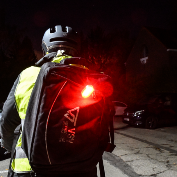 fietser met losse fietsverlichting op rugzak, rood achterlicht