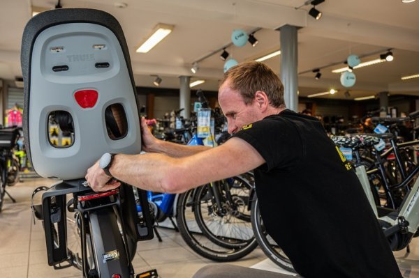 fietshandelaar die fietsstoeltje monteert op fiets