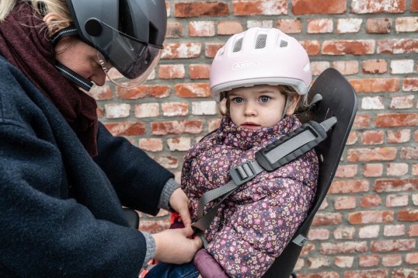 moeder maakt gordels van fietsstoeltje vast bij kind