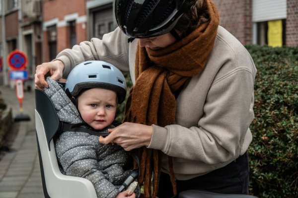 moeder die kind vastmaakt in een fietsstoel