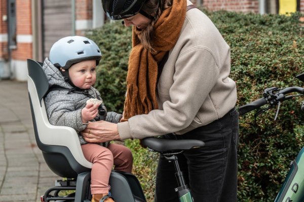 ouder dat kind in fietsstoeltje zet