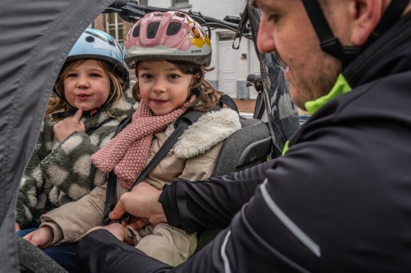 man die gordels vastklikt bij kind in een bakfiets