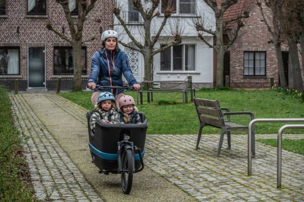 vrouw die met bakfiets met 2 kinderen fietst