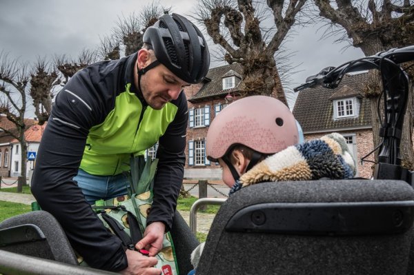 man die bagage vastmaakt in een bakfiets