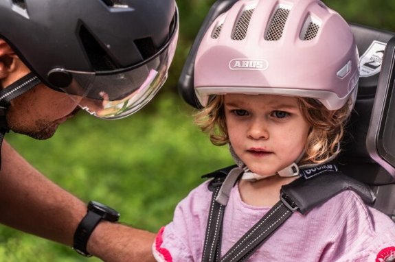 vader die kind veilig vastzet in een fietsstoeltje