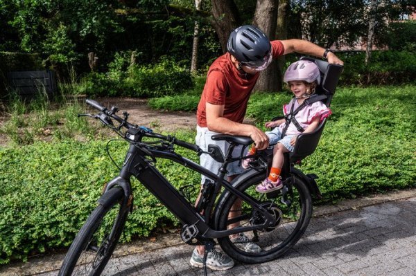 kind in fietsstoel achterop, vader die gordels vastmaakt