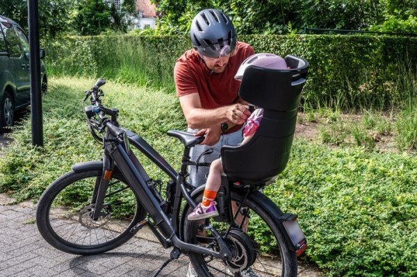 vader die kind in een fietsstoel zet
