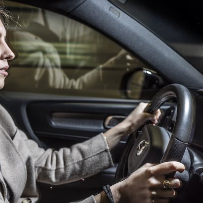 vrouw die geconcentreerd rijdt met handen aan het stuur