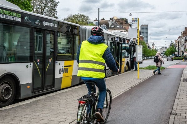 fietser op fietspad naast bushalte waar passagier afstapt
